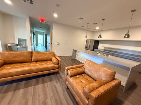 A living room with a brown leather couch and a brown leather chair.