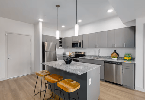 A modern kitchen with a marble countertop and stainless steel appliances.