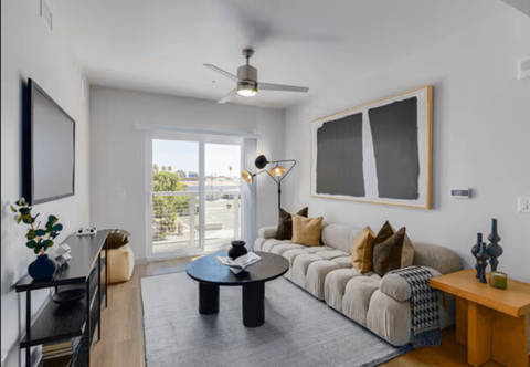 A living room with a couch, coffee table, and a ceiling fan.