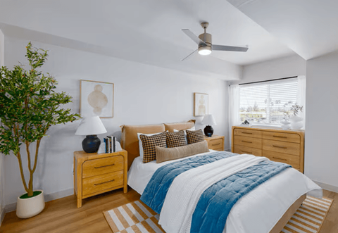 A bedroom with a bed, nightstand, and a ceiling fan.