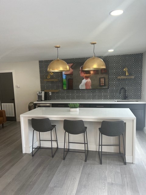 A kitchen with a white counter and black chairs.