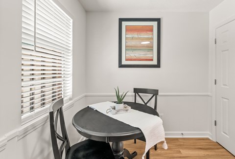 A dining room with a table, chairs and a picture on the wall.