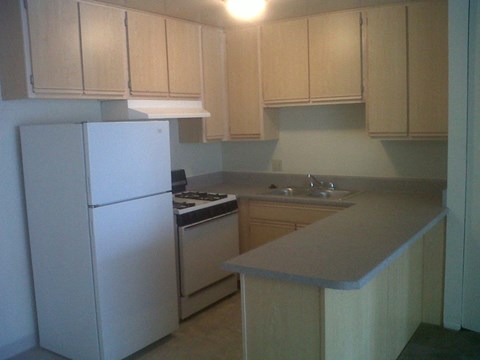 an empty kitchen with white appliances and white cabinets