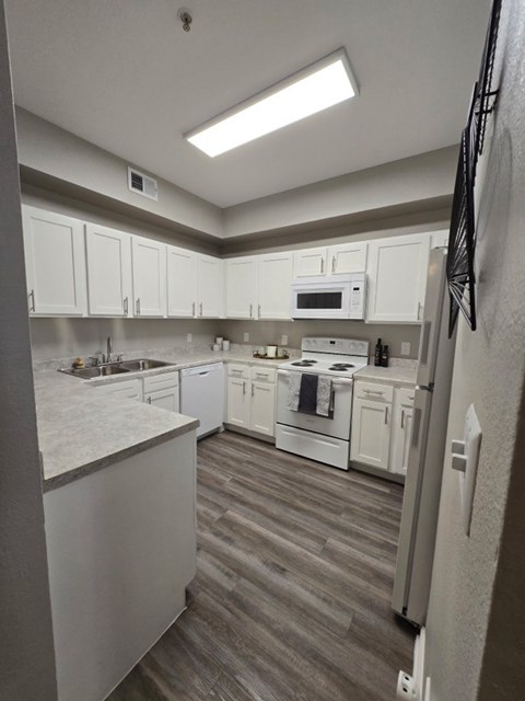 A kitchen with white cabinets and a grey floor.