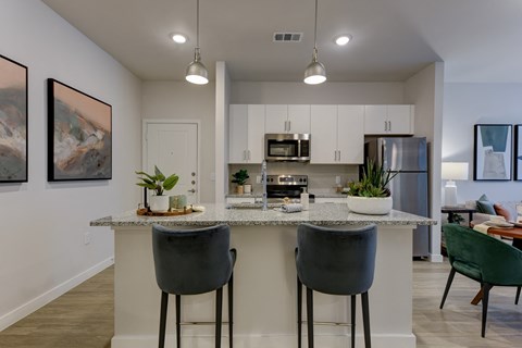 an open kitchen with a granite counter top with two stools
