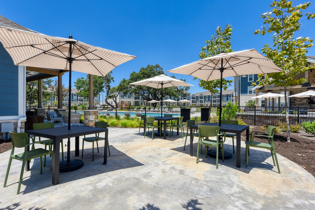 a patio with tables and umbrellas and chairs and a pool at Estraya Boerne, Texas