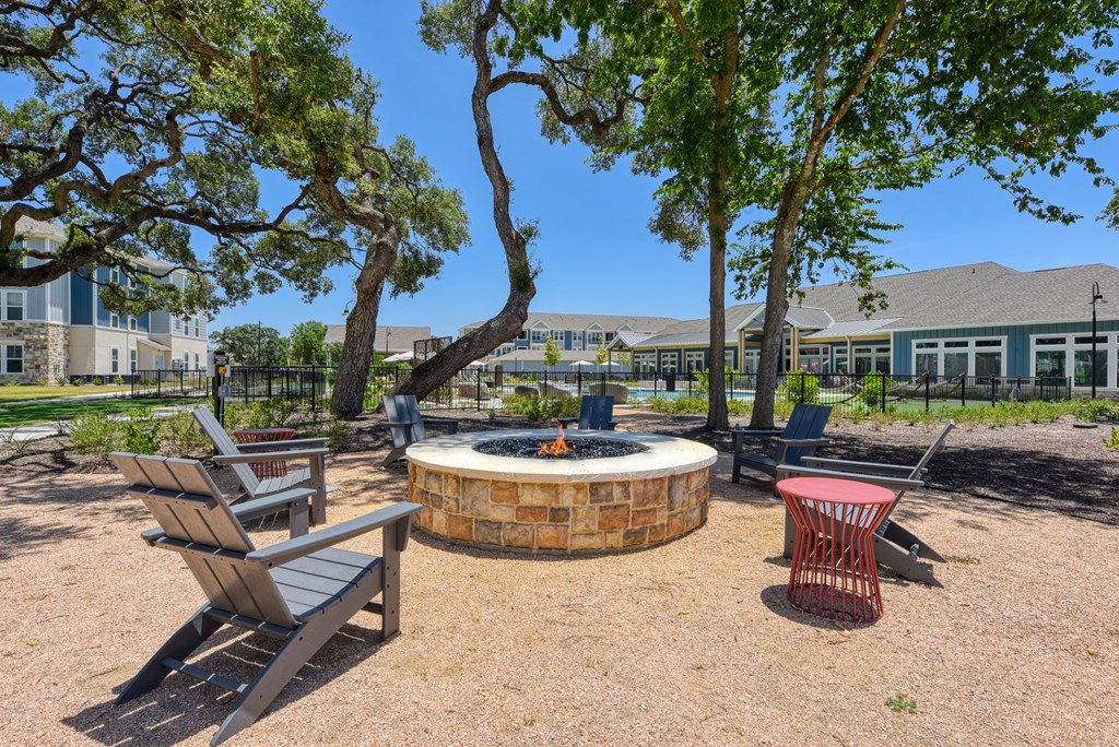 a fire pit with chairs and trees and a building in the background at Estraya Boerne, Boerne