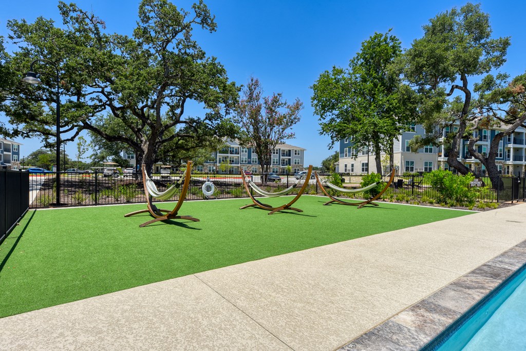 a yard with hammocks and a pool with trees and buildings at Estraya Boerne, Texas