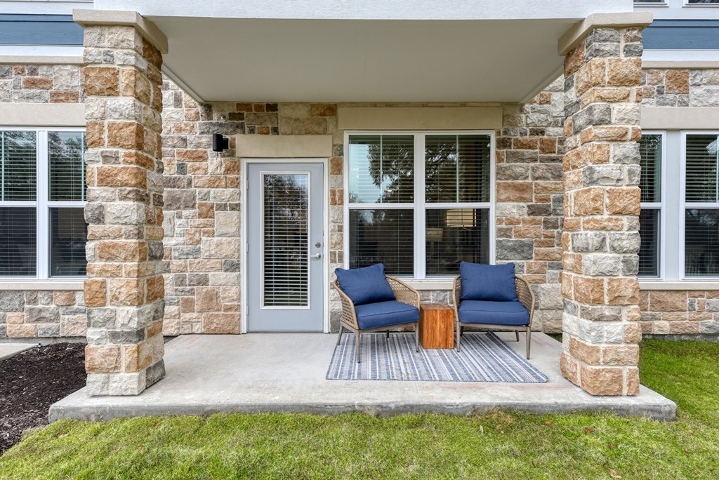 a front porch of a house with two chairs and a table at Estraya Boerne, Texas, 78006