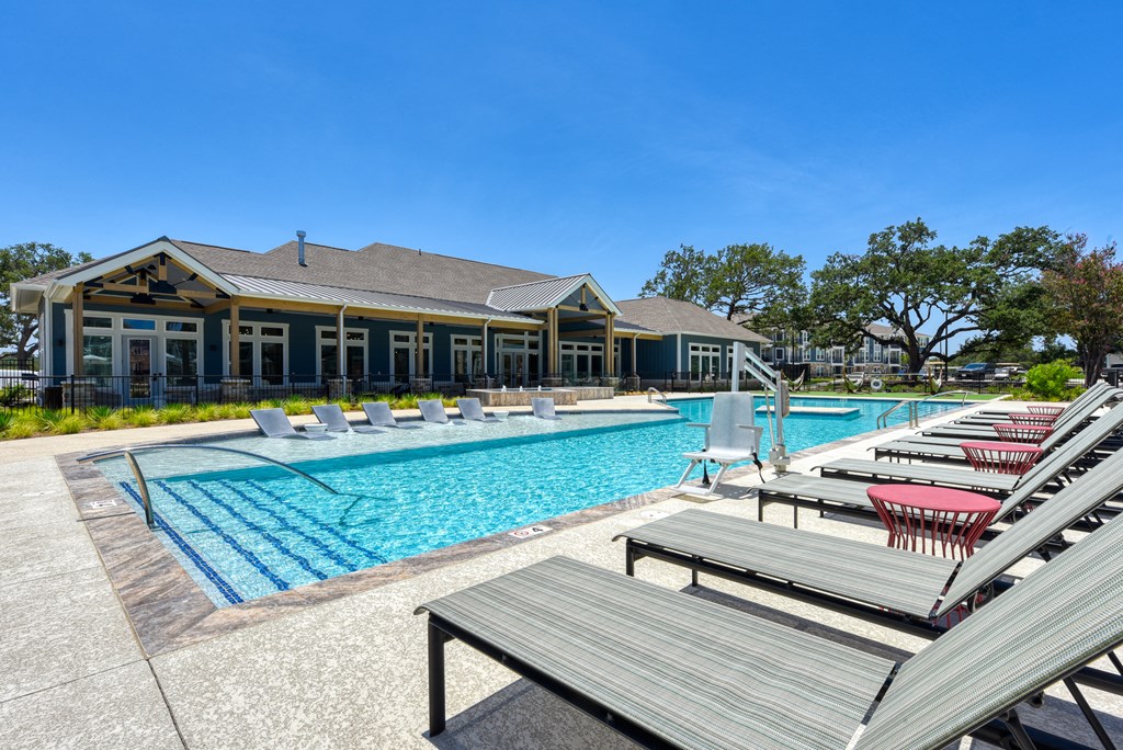 a swimming pool with lounge chairs and a building in the background at Estraya Boerne, Boerne, TX, 78006