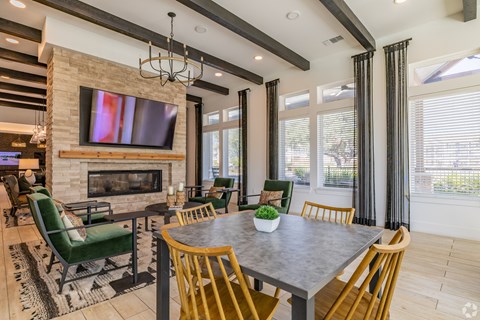 A modern dining room with a stone fireplace and a large TV above it.