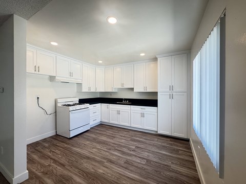A kitchen with white cabinets and a black countertop.