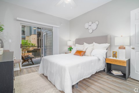 A bedroom with a large bed and a sliding glass door.
