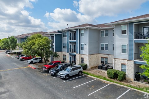 A parking lot with cars and apartment buildings in the background.