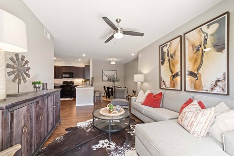 A living room with a grey couch and a painting of a horse on the wall.