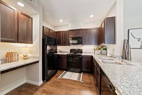 A kitchen with dark brown cabinets and black appliances. at Residences at the Landing, Texas, 78028