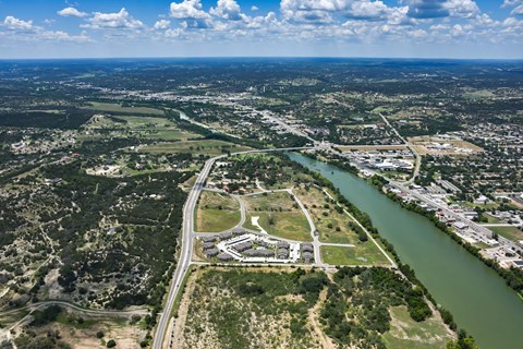 A river flows through a city with a bridge crossing over it. at Residences at the Landing, Kerrville