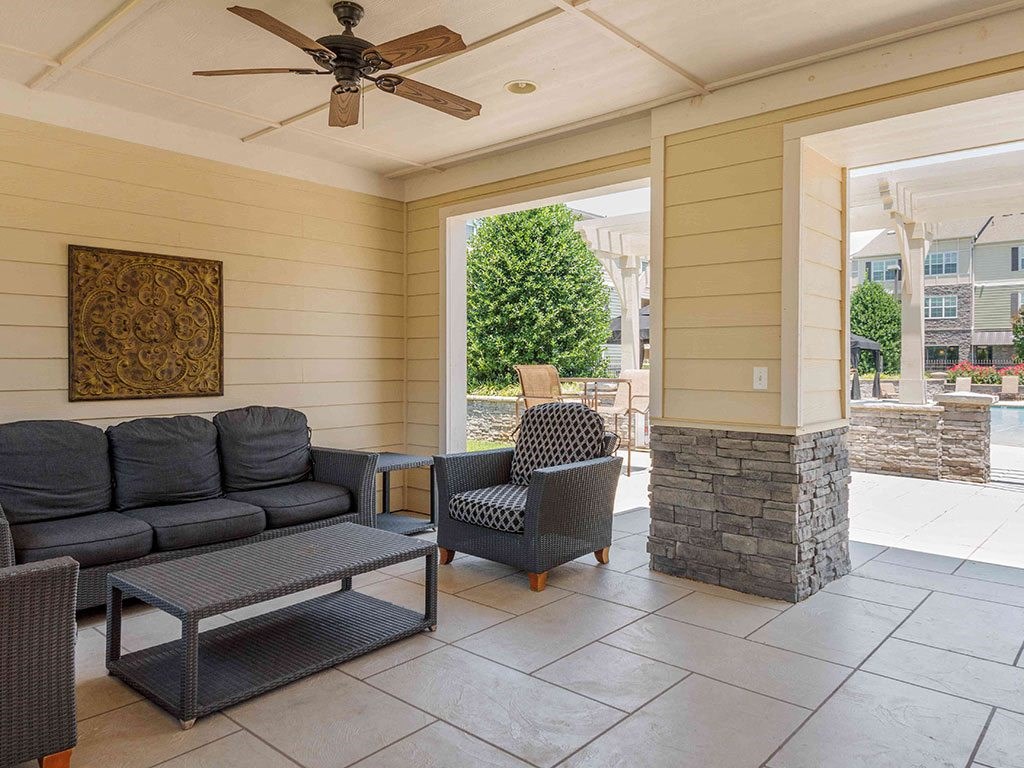 a covered porch with couches and chairs and a ceiling fan