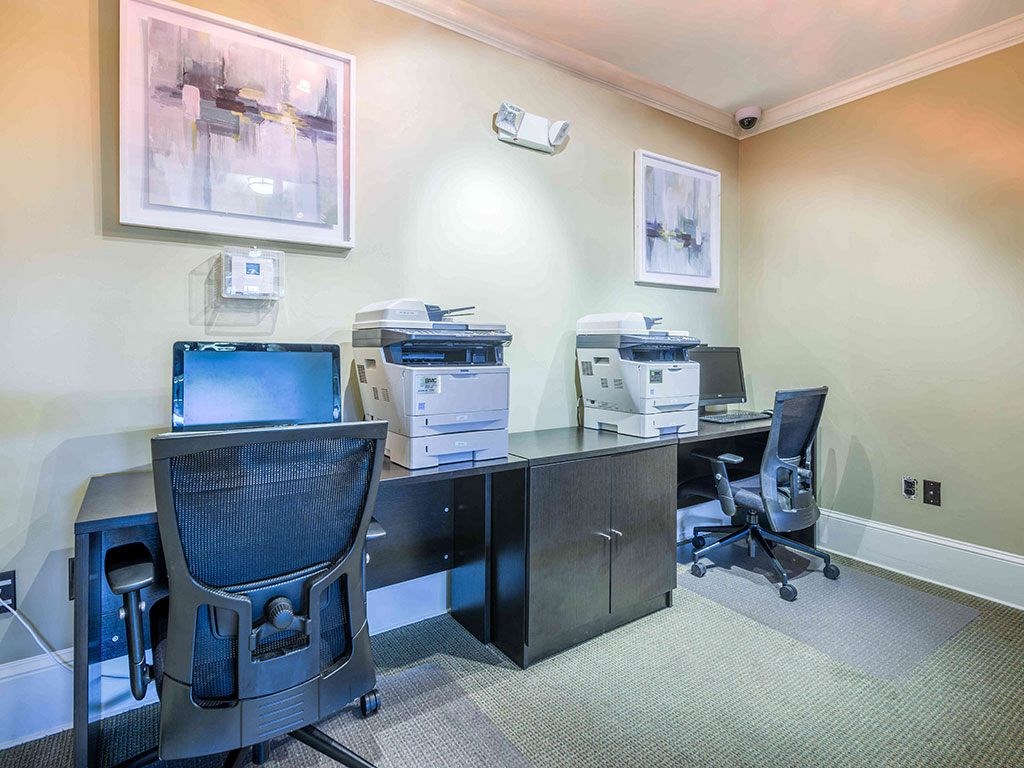 a office with two desks and two computers and printers