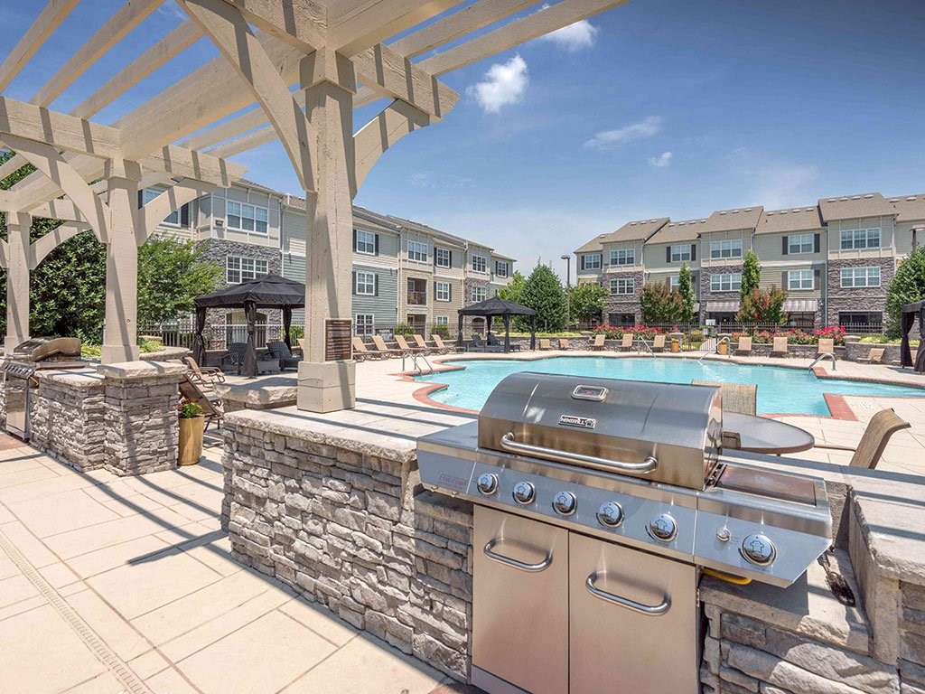 a barbecue grill on a patio next to a swimming pool