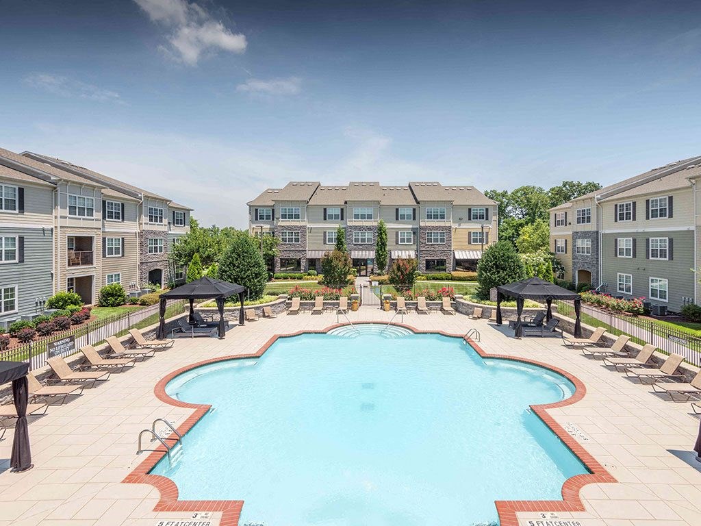 an aerial view of an outdoor pool with lounge chairs and apartment buildings