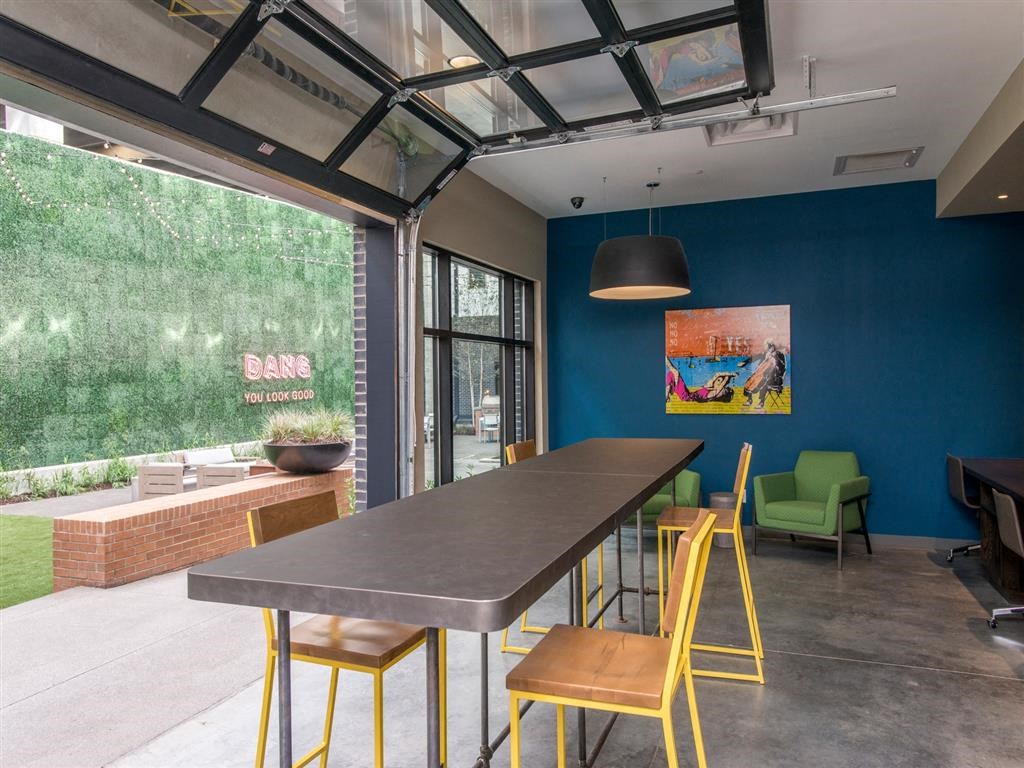 a communal table and chairs in a room with a large window