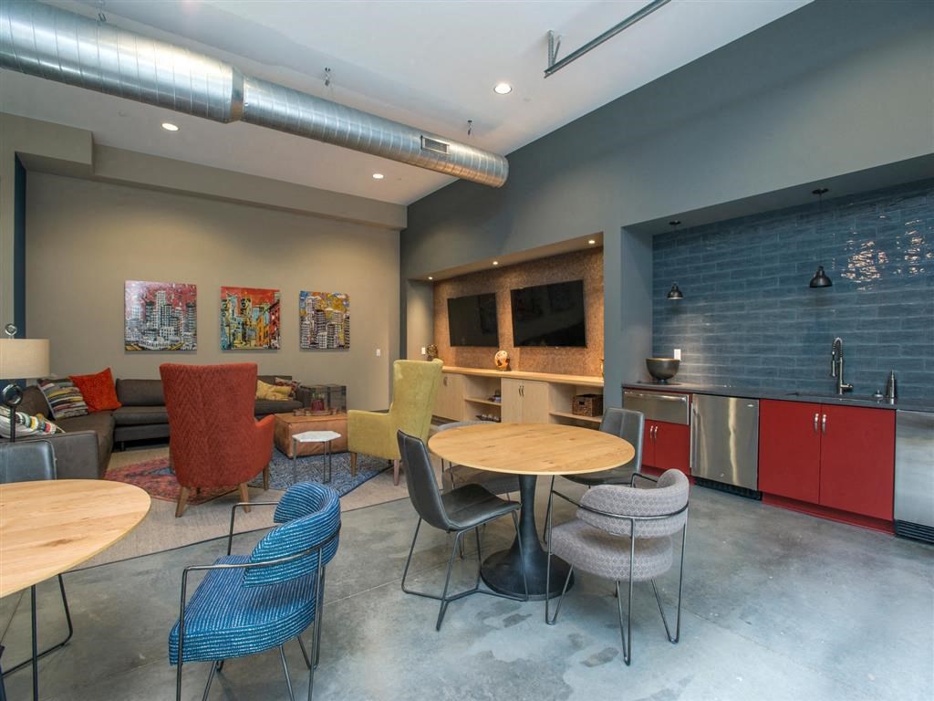 a lounge area with tables and chairs and a kitchen