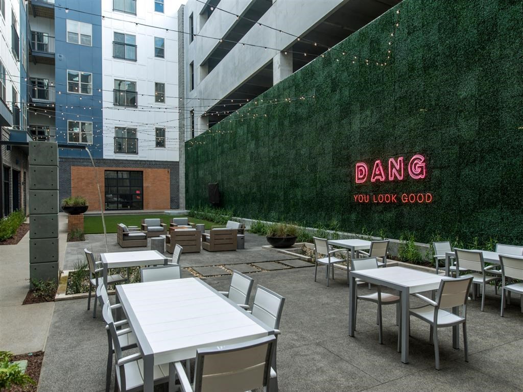 an outdoor restaurant with tables and chairs and a green wall