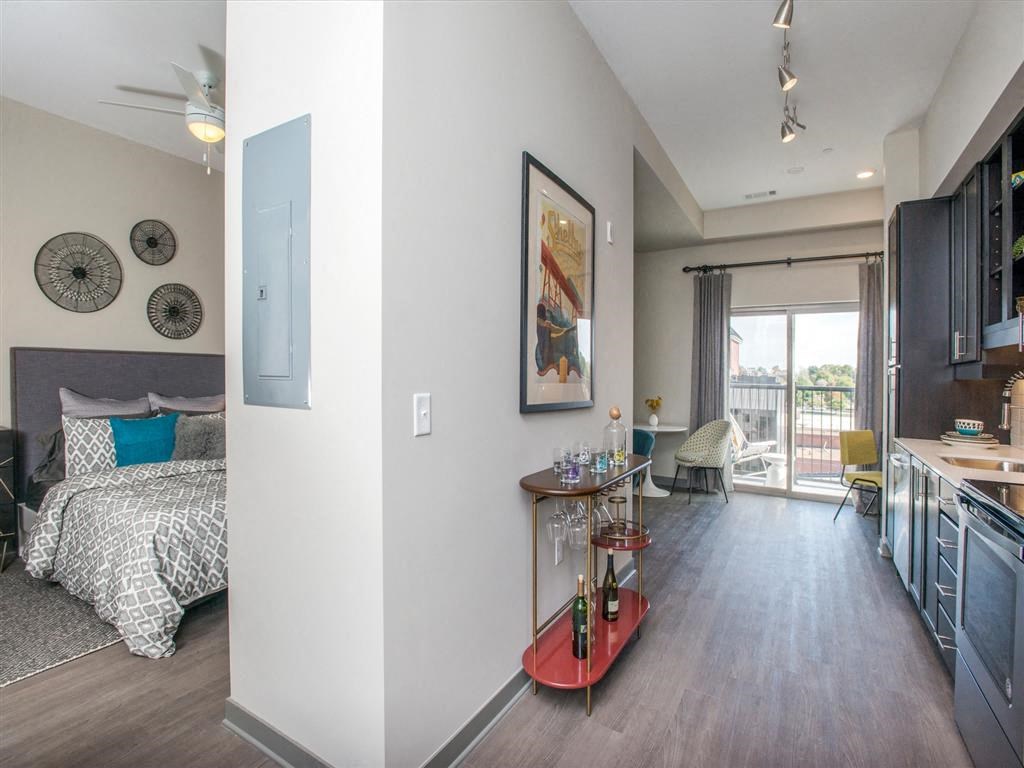 a bedroom and living room with a kitchen and a balcony