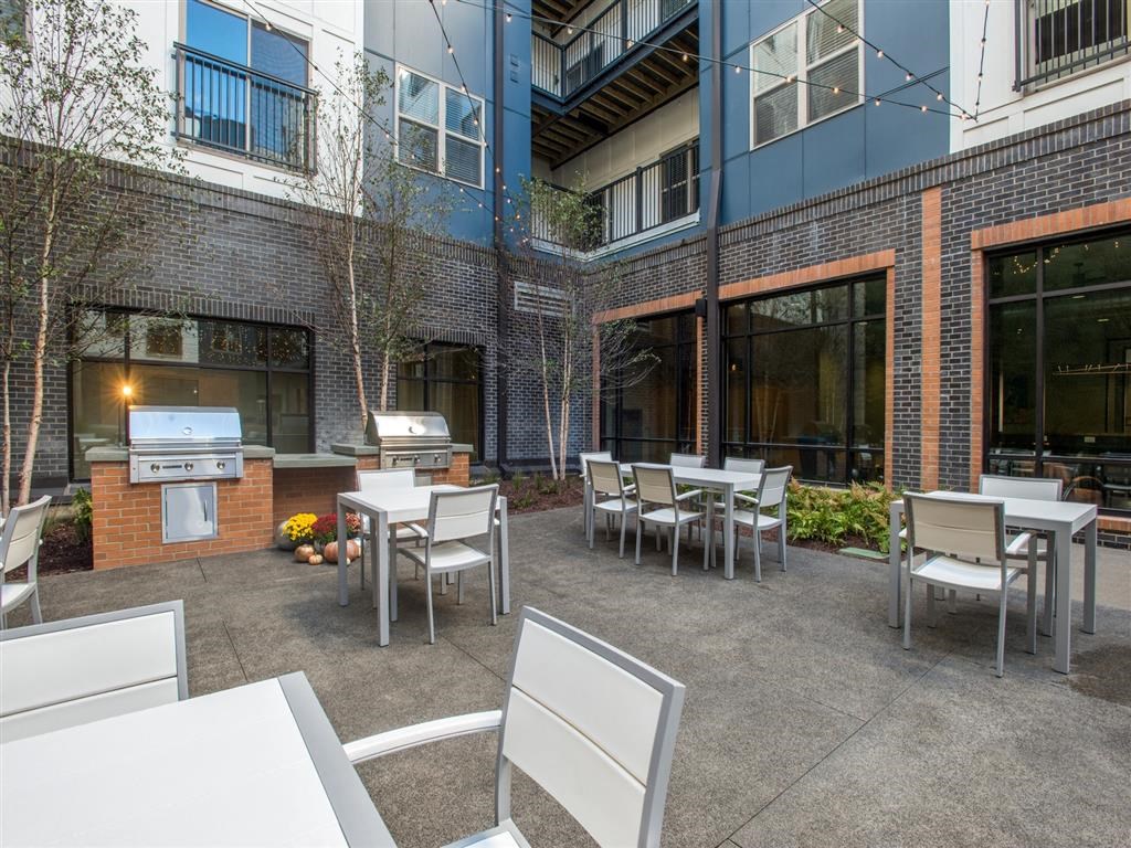 an outside patio with tables and chairs and a grill
