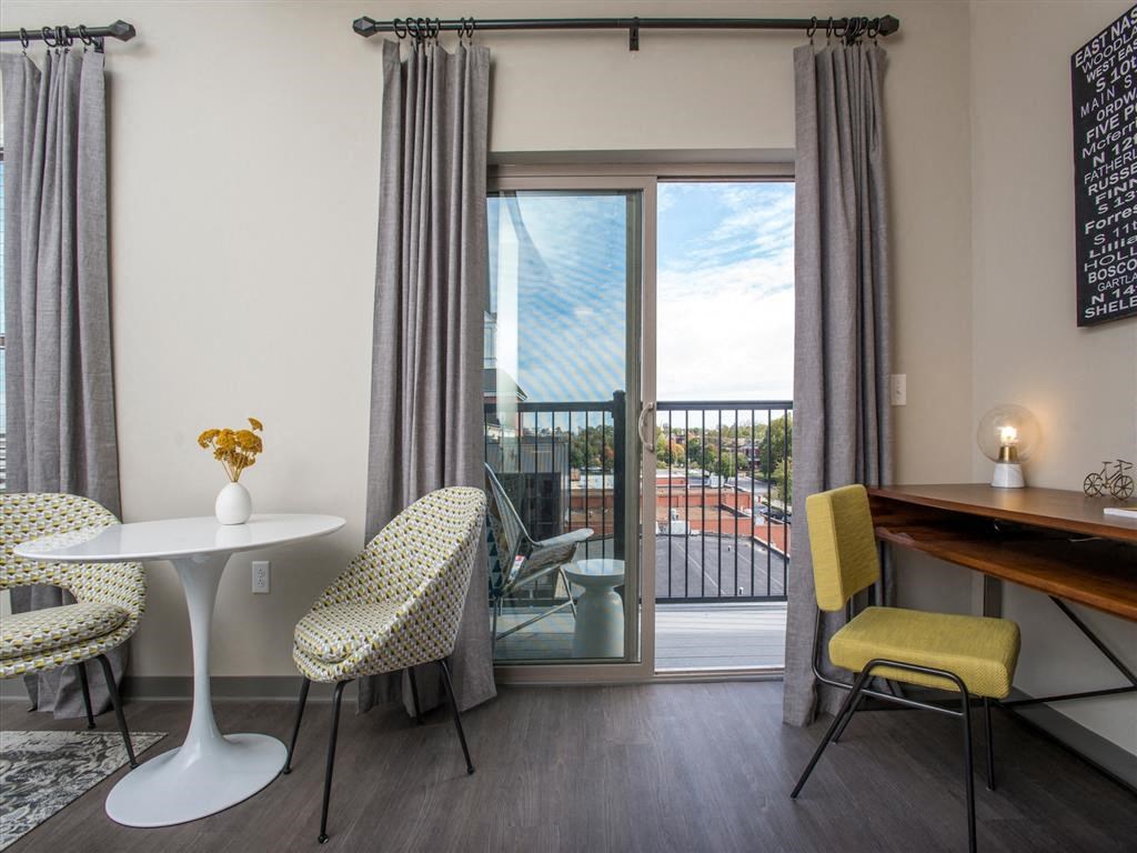 a living room with a table and chairs and a balcony