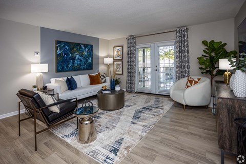 A living room with a large painting on the wall and a sofa with a black and white patterned throw pillow.