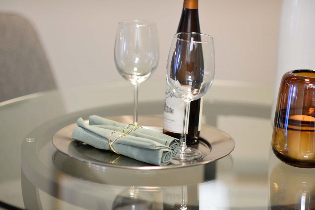 A bottle of wine is on a table with two glasses and a plate with two napkins.at Addison at Sutherland, Tennessee  