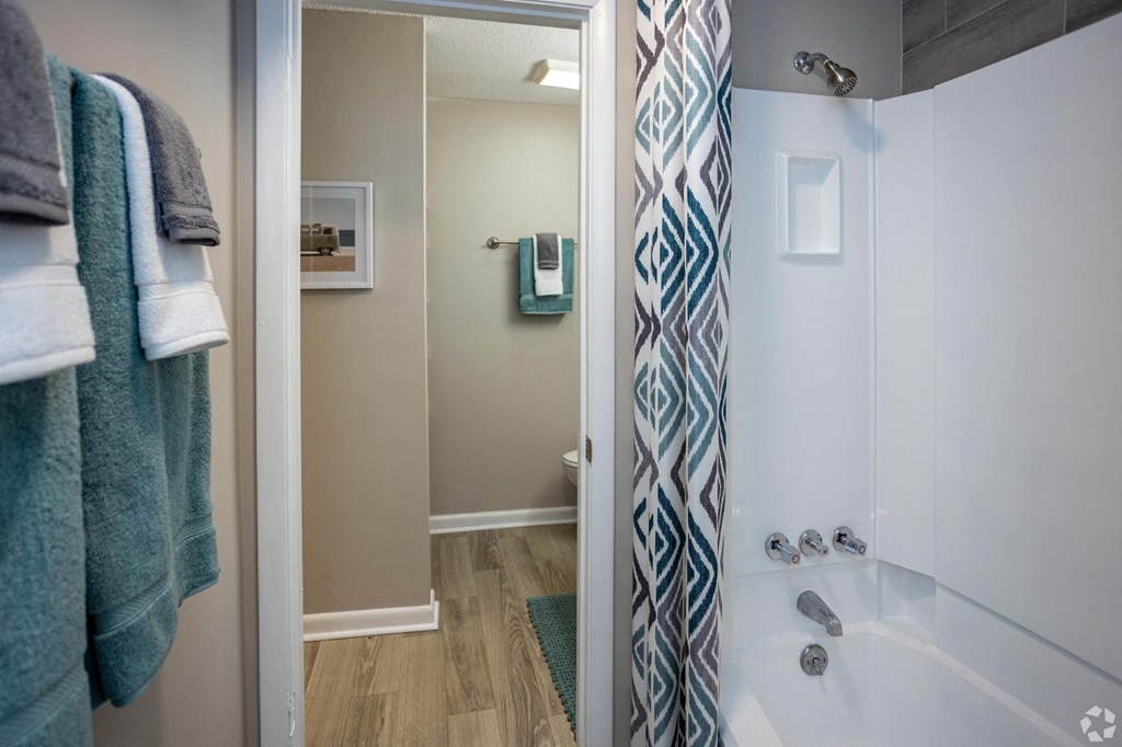 A bathroom with a white tub and a shower with a blue and white curtain.at Addison at Sutherland, Tennessee  