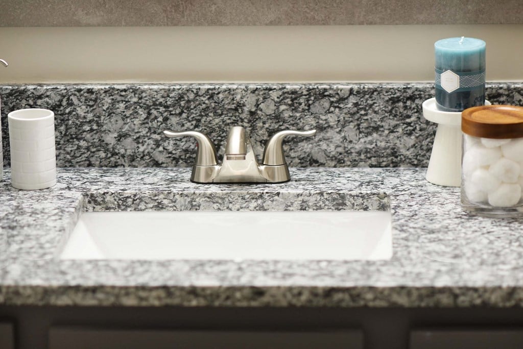 A bathroom sink with a marble countertop and a white faucet.at Addison at Sutherland, Knoxville, 37909  