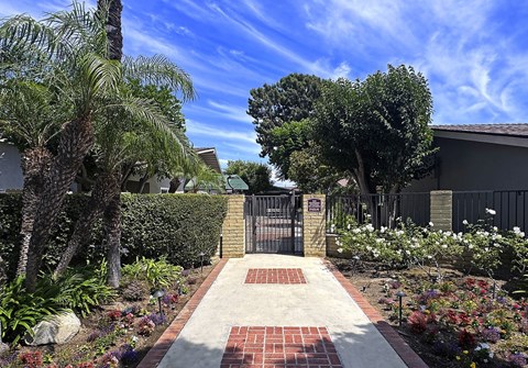 A garden with a brick pathway leading to a gate.