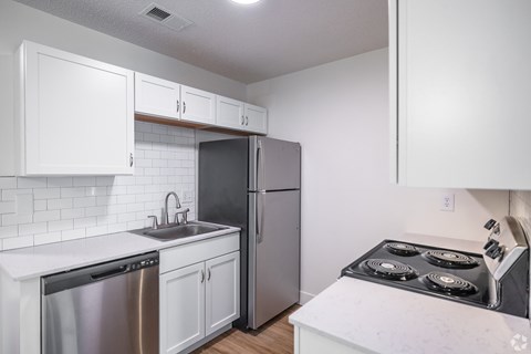 A kitchen with white cabinets and a stainless steel refrigerator.