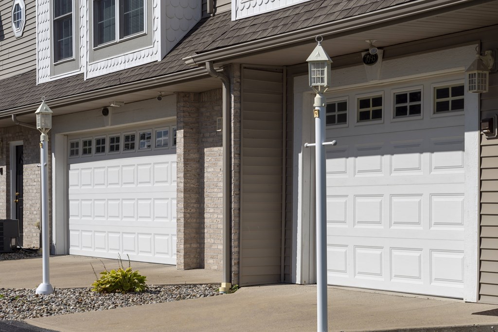 A house with two white garage doors and a lamp post in front.