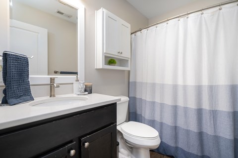 A white sink with a blue towel and a white toilet in a bathroom.