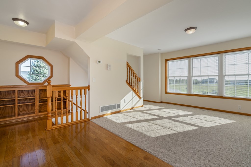 A spacious room with a staircase and a large window.