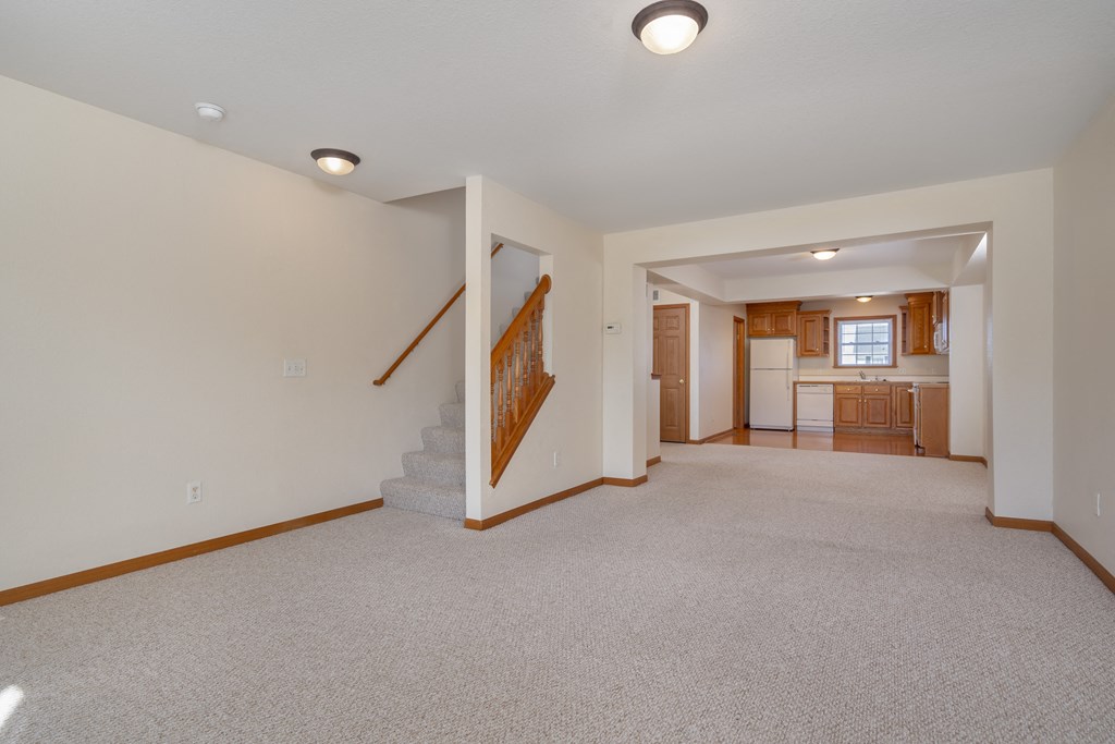 A spacious living room with a staircase leading to the upper floor.