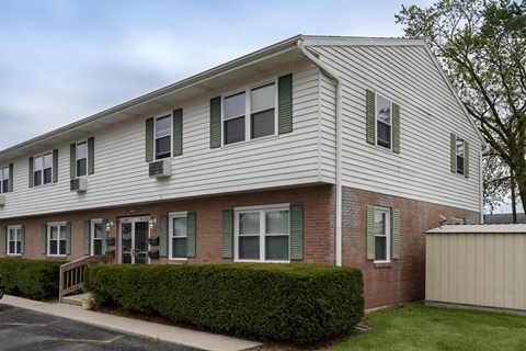 A two-story building with a grey roof and green shutters.