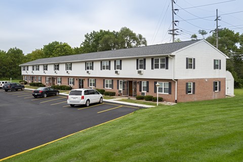 A white building with a parking lot in front.