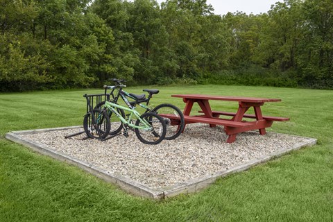 A green bike is parked next to a red picnic table.