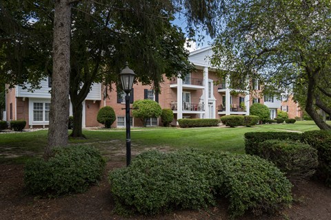 A large building with a white front porch and a black lamp post.