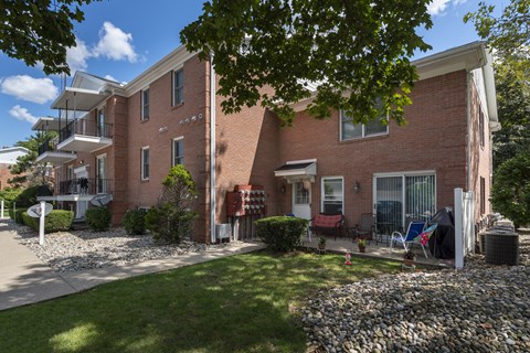 A red brick apartment building with a green lawn in front.