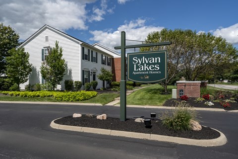A sign for Sylvan Lakes Apartment Homes stands in front of a building.