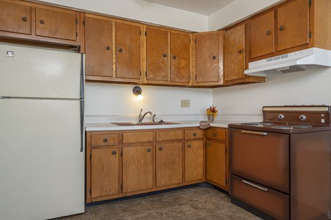 A kitchen with brown cabinets and a white refrigerator.