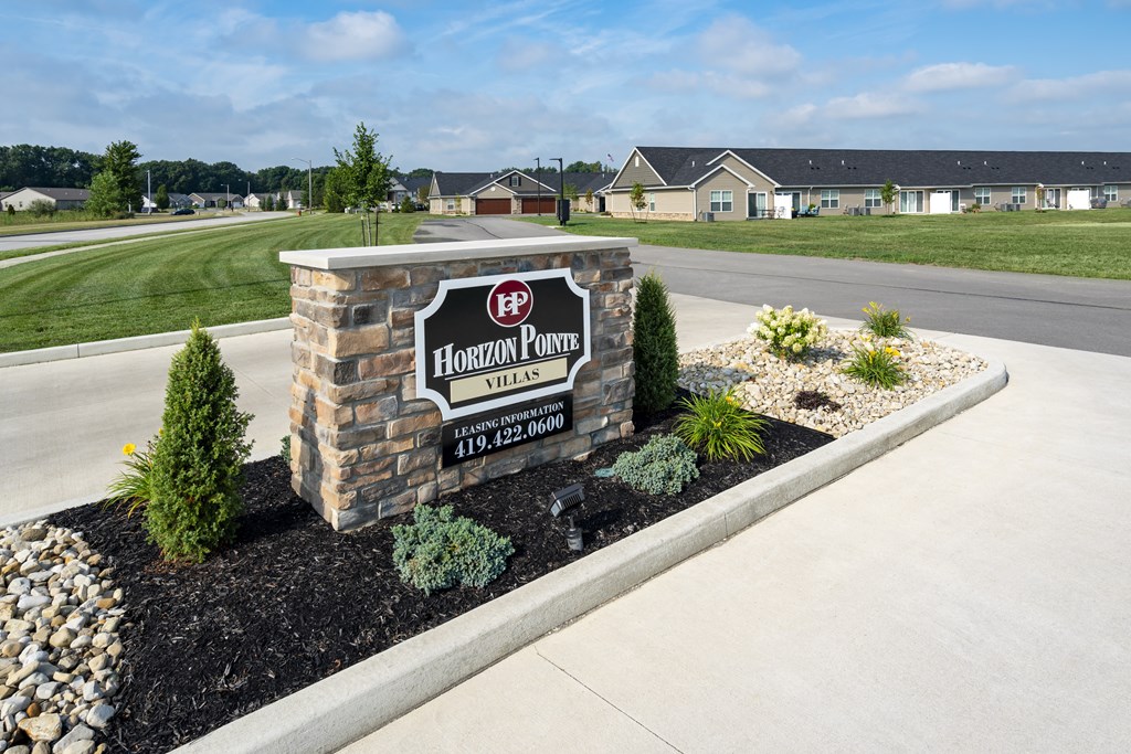 A sign for Horizon Point Village stands in front of a grassy area.
