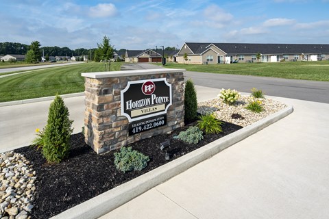 A sign for Horizon Point Village stands in front of a grassy area.